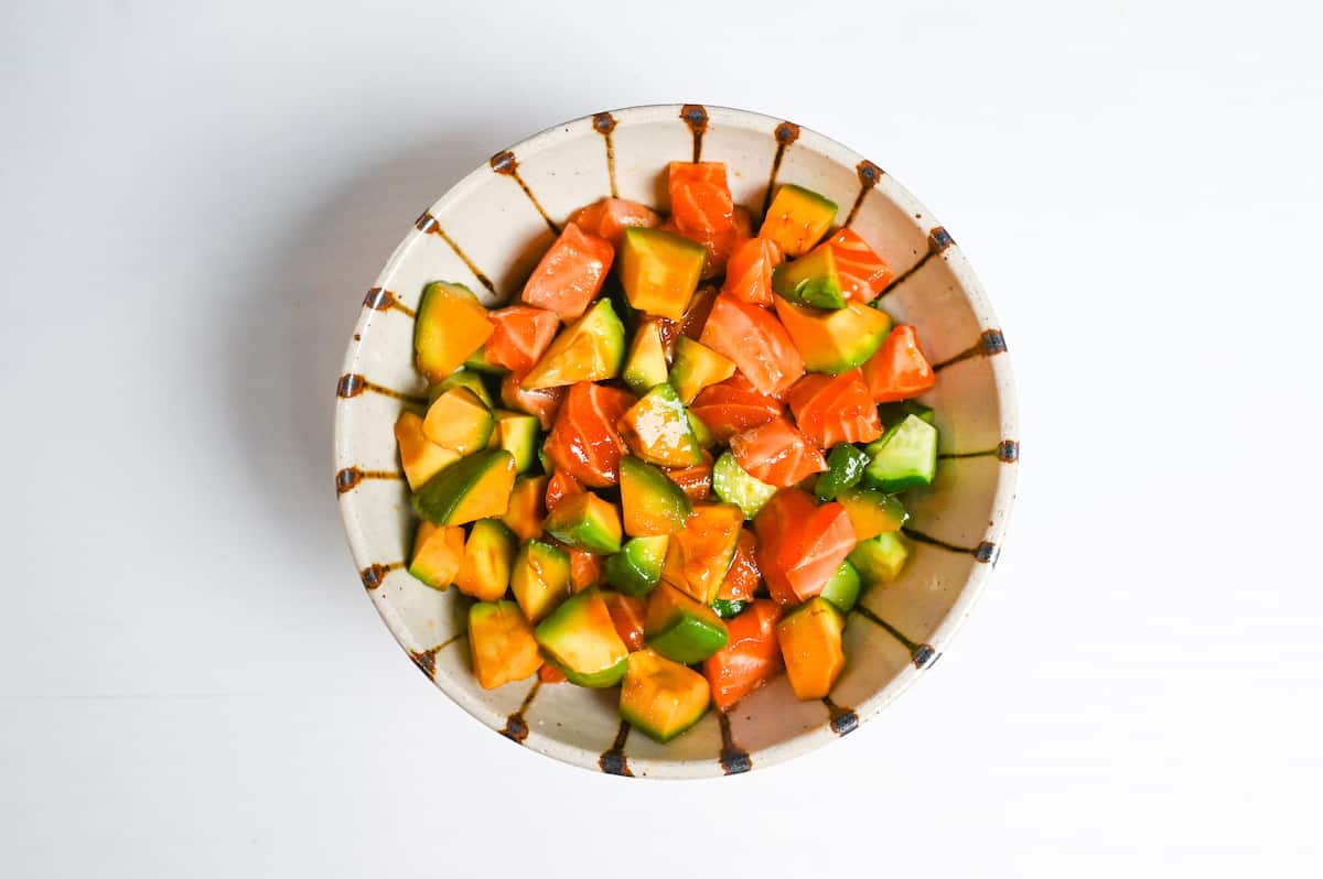 marinated salmon and avocado over rice in a stripey bowl