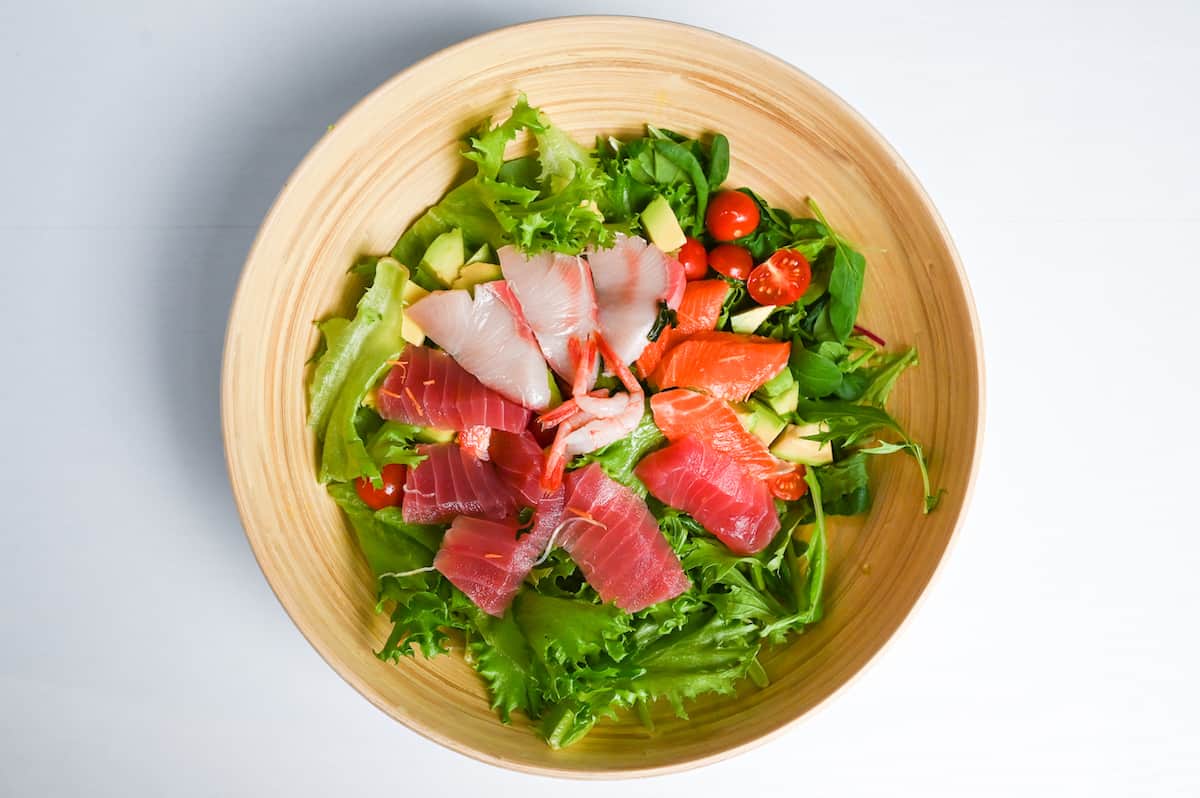salad vegetables topped with sashimi salmon, tuna, yellowtail and sweet shrimp