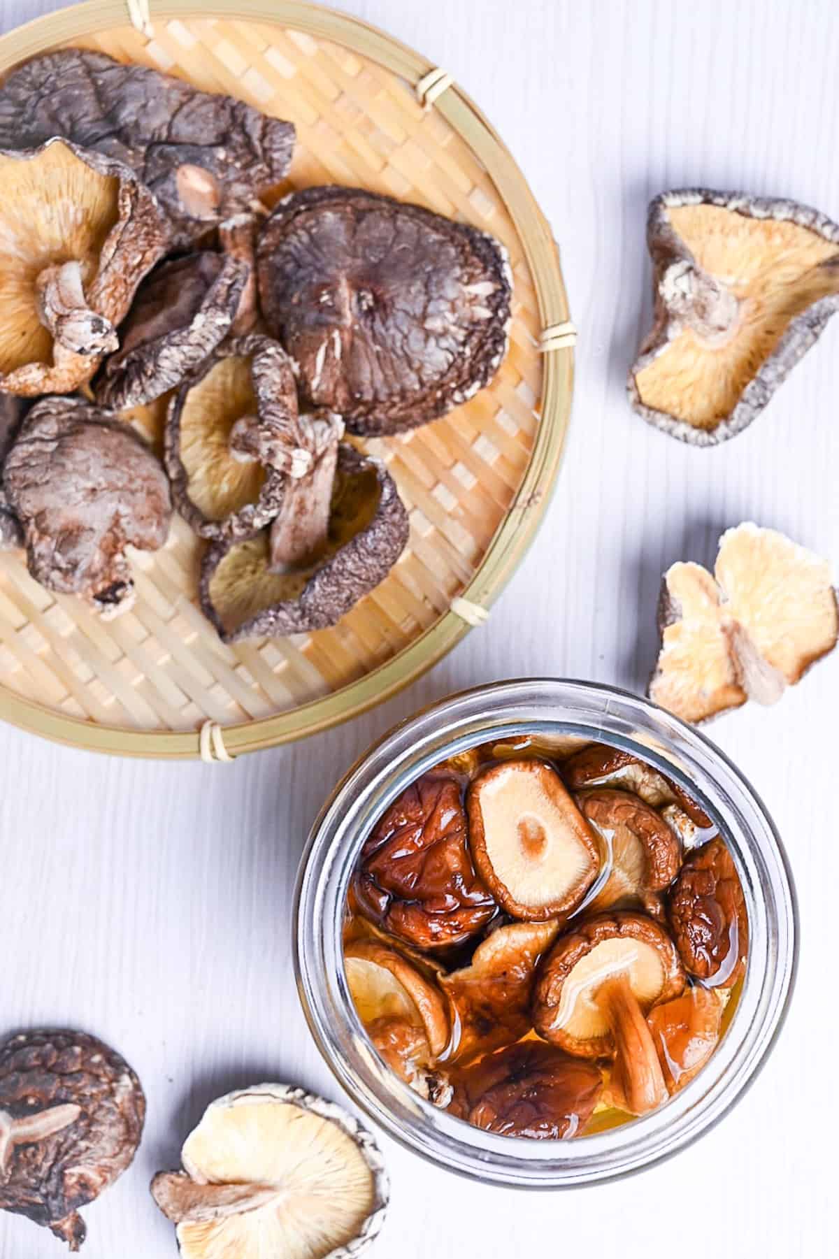 top down view of shiitake dashi in a jar next to loose dried shiitake mushrooms