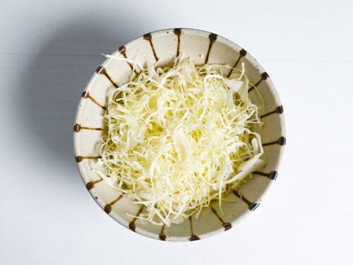 rice topped with shredded cabbage in a stripy bowl