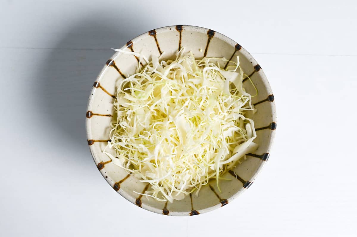 rice topped with shredded cabbage in a stripy bowl