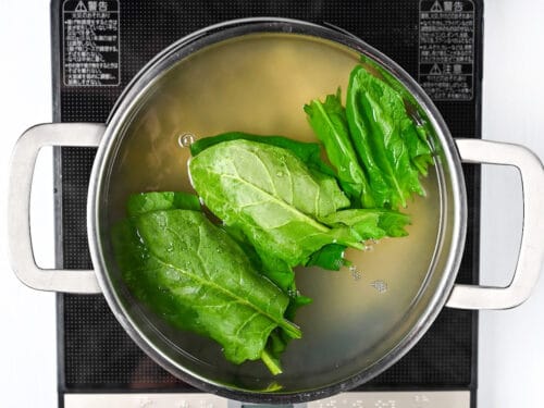 cooking spinach leaves together with ramen noodles
