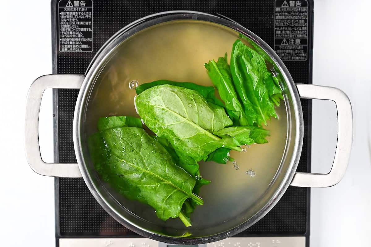 cooking spinach leaves together with ramen noodles