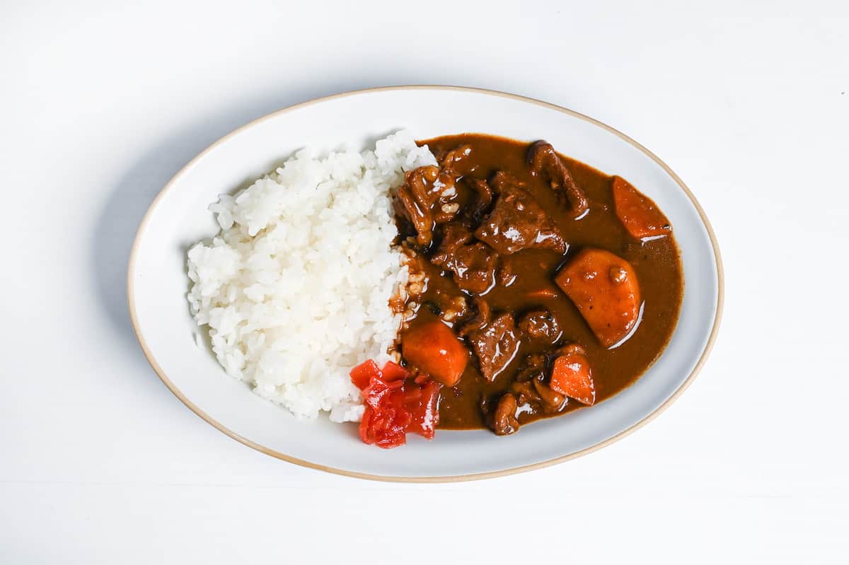 Homemade Japanese beef curry from scratch on a oval plate with rice and fukujinzuke pickles