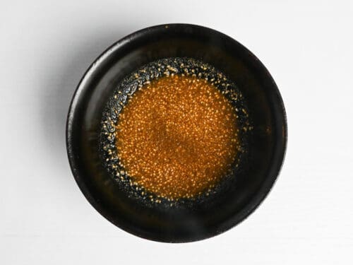 Sake, mirin, soy sauce, ground sesame, grated ginger and wasabi paste mixed in a bowl