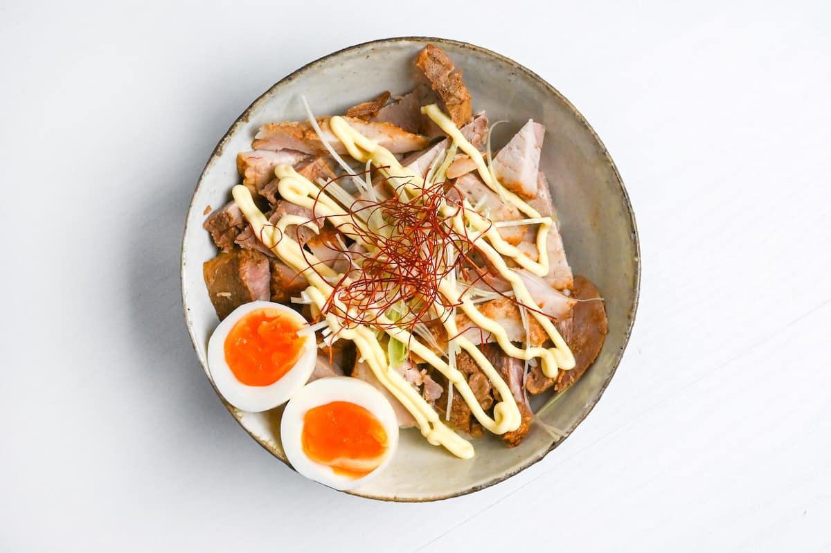 Chashu don topped with soft boiled egg, Japanese mayonnaise, shreds of green onion and chili threads.