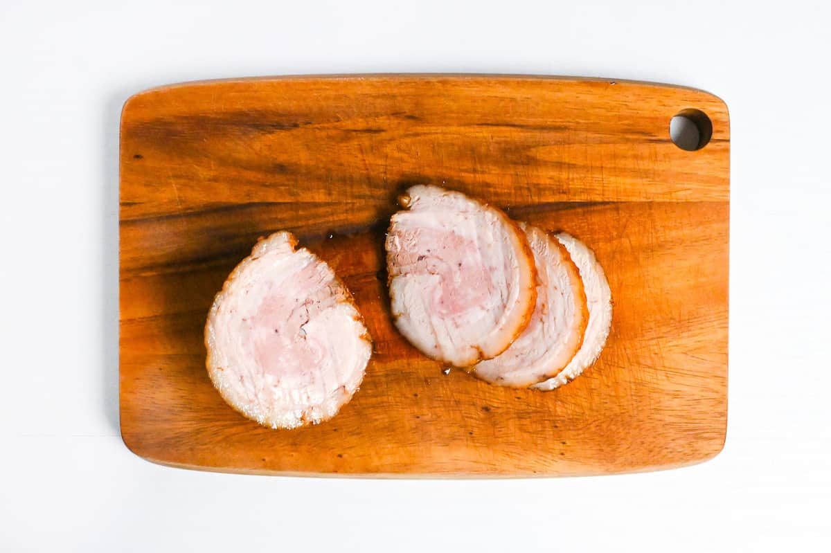 thick slices of homemade chashu on a wooden chopping board