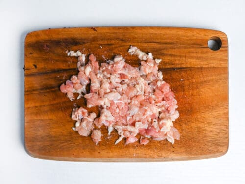 finely chopped chicken thigh on a wooden chopping board