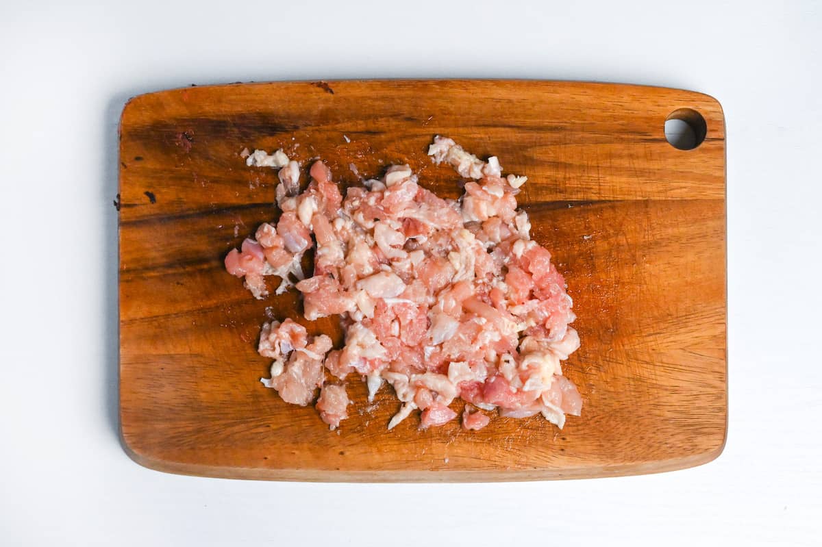 finely chopped chicken thigh on a wooden chopping board