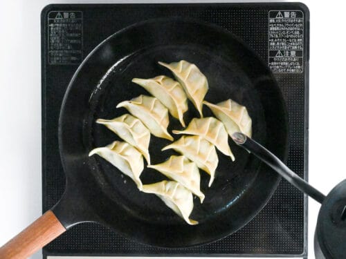 pouring freshly boiled water over cooking gyoza