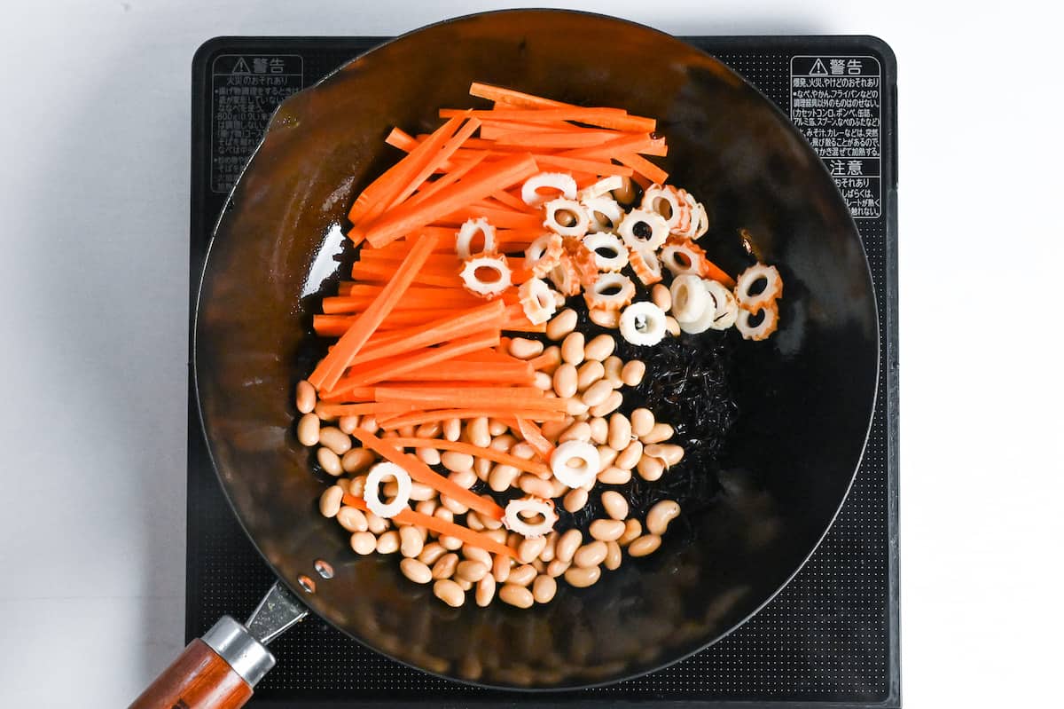 stir frying carrot, chikuwa, soy beans and rehydrated hijiki seaweed in a large wok
