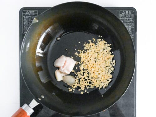 Frying garlic and ginger with a cube of beef fat