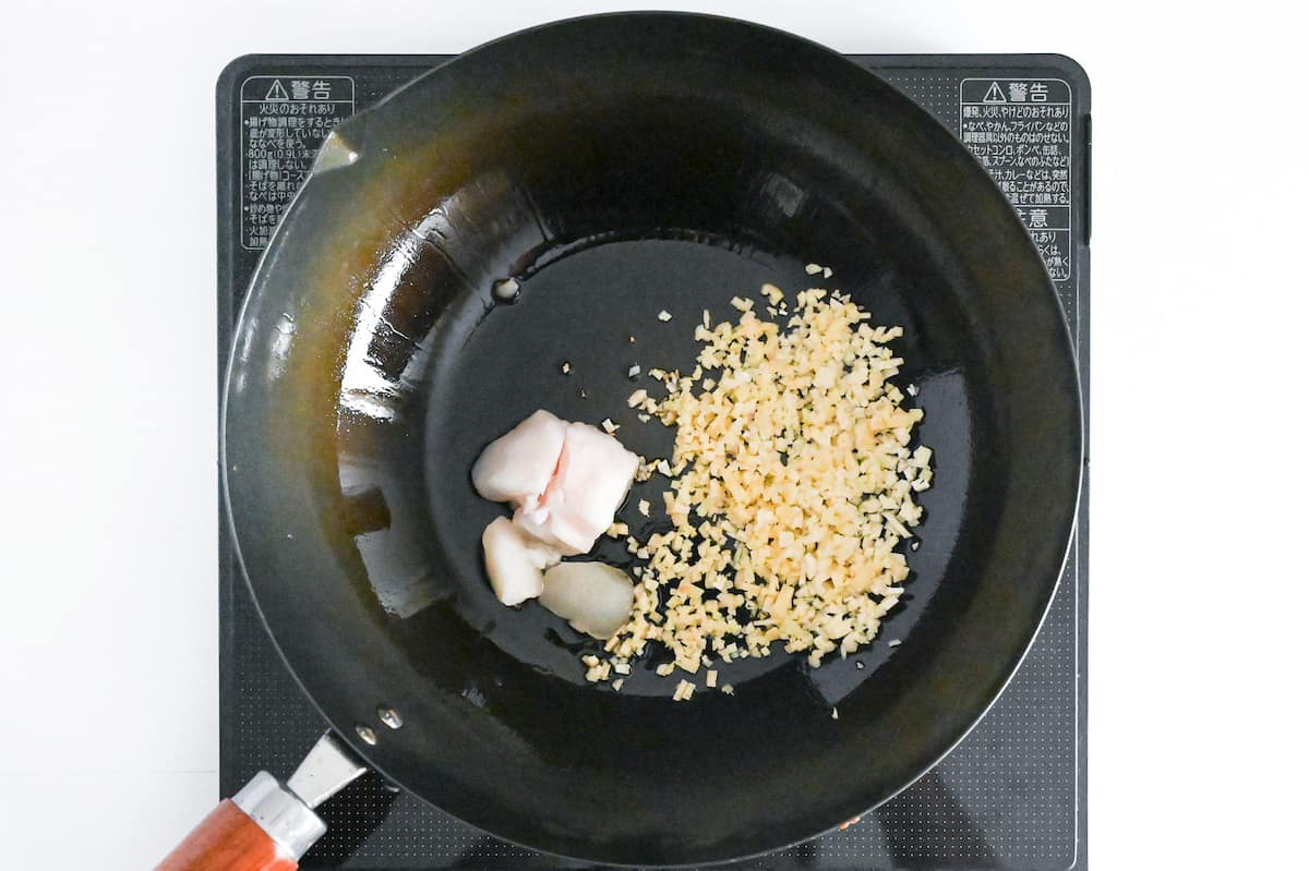 Frying garlic and ginger with a cube of beef fat