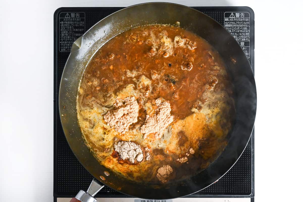 adding coriander, marmalade, ground cloves, cardamom and ginger powder to simmering homemade curry roux