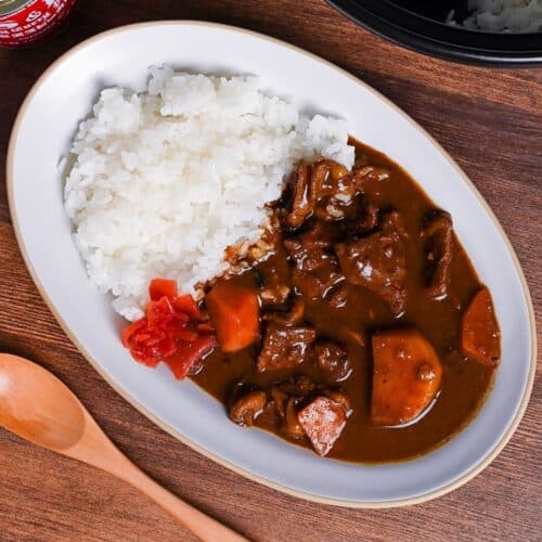 Homemade Japanese beef curry rice from scratch served on a white oval plate with fukujinzuke pickles