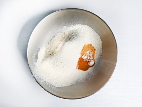sifted flour in a bowl with baking powder, cinnamon and nutmeg