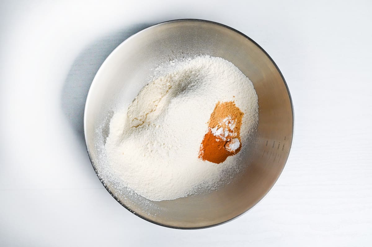 sifted flour in a bowl with baking powder, cinnamon and nutmeg