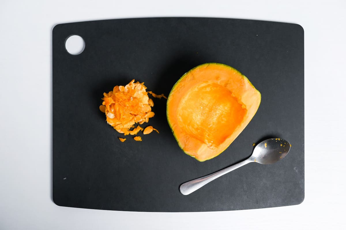 Kabocha Japanese squash on a black chopping board with seeds scooped out