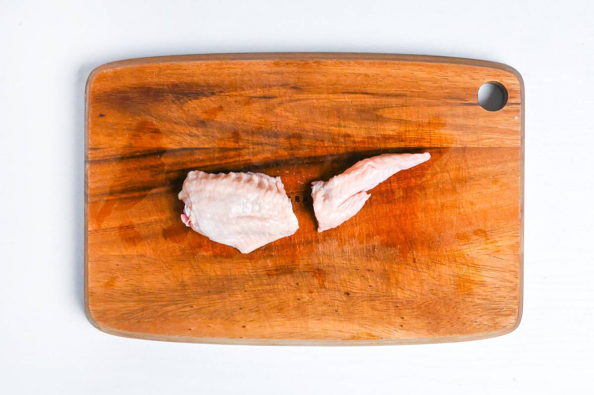 chicken wing cut into wingette and tip on a wooden chopping board