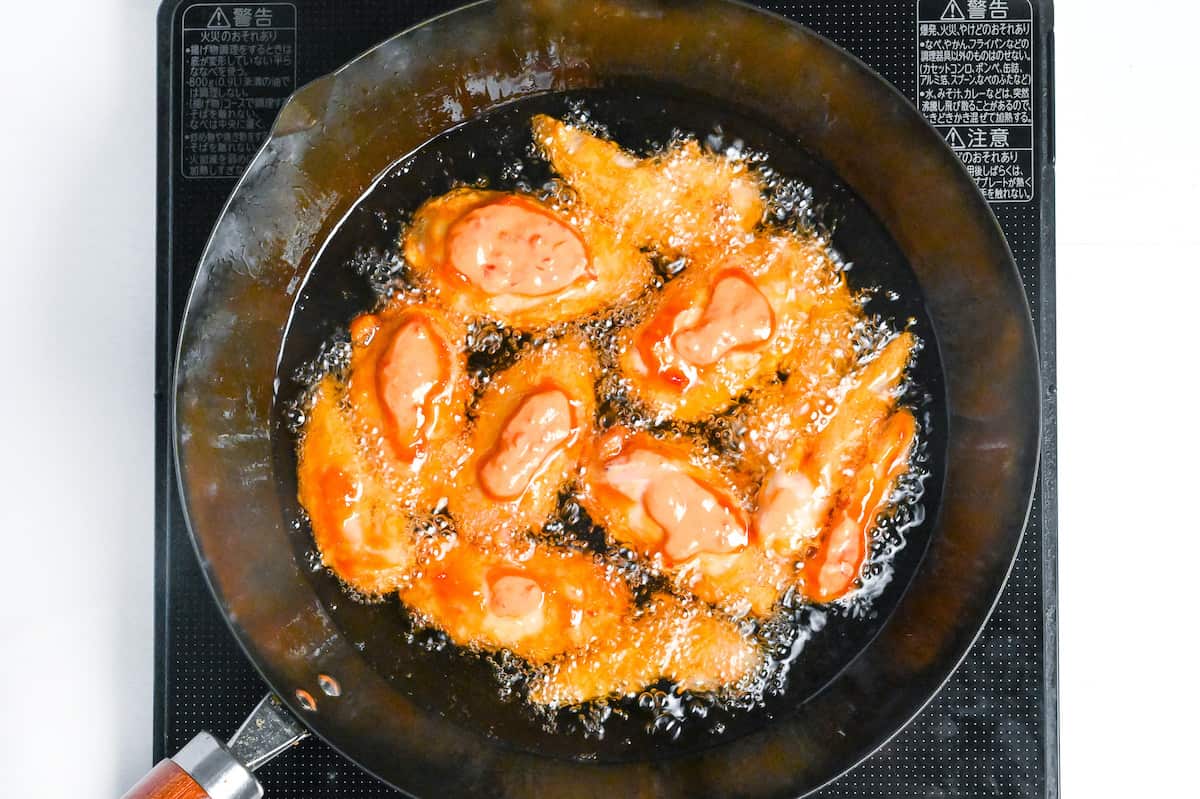 Shallow frying karami chicken wings in a wok at a lower temperature