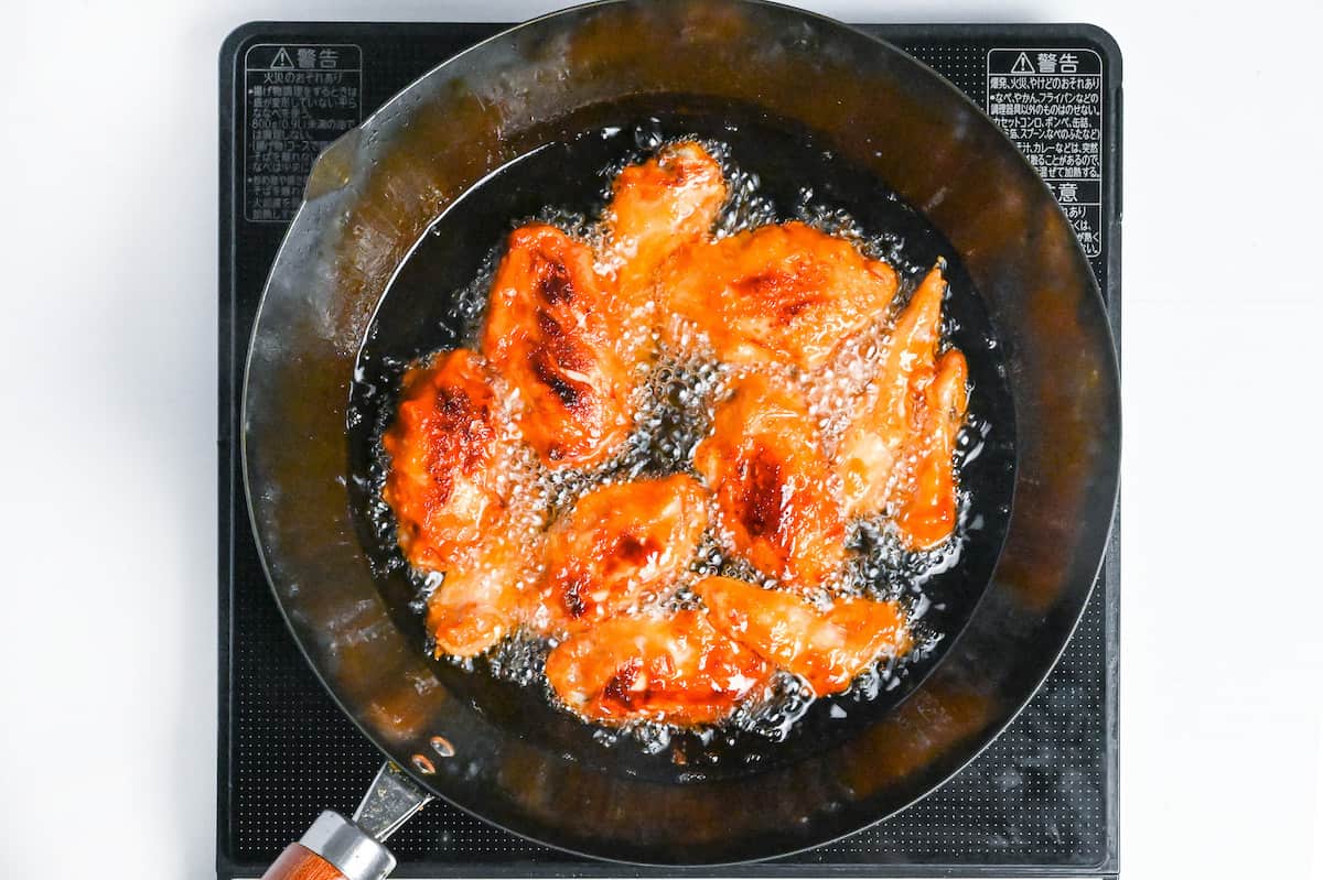 Shallow frying karami chicken wings at a higher temperature in a wok