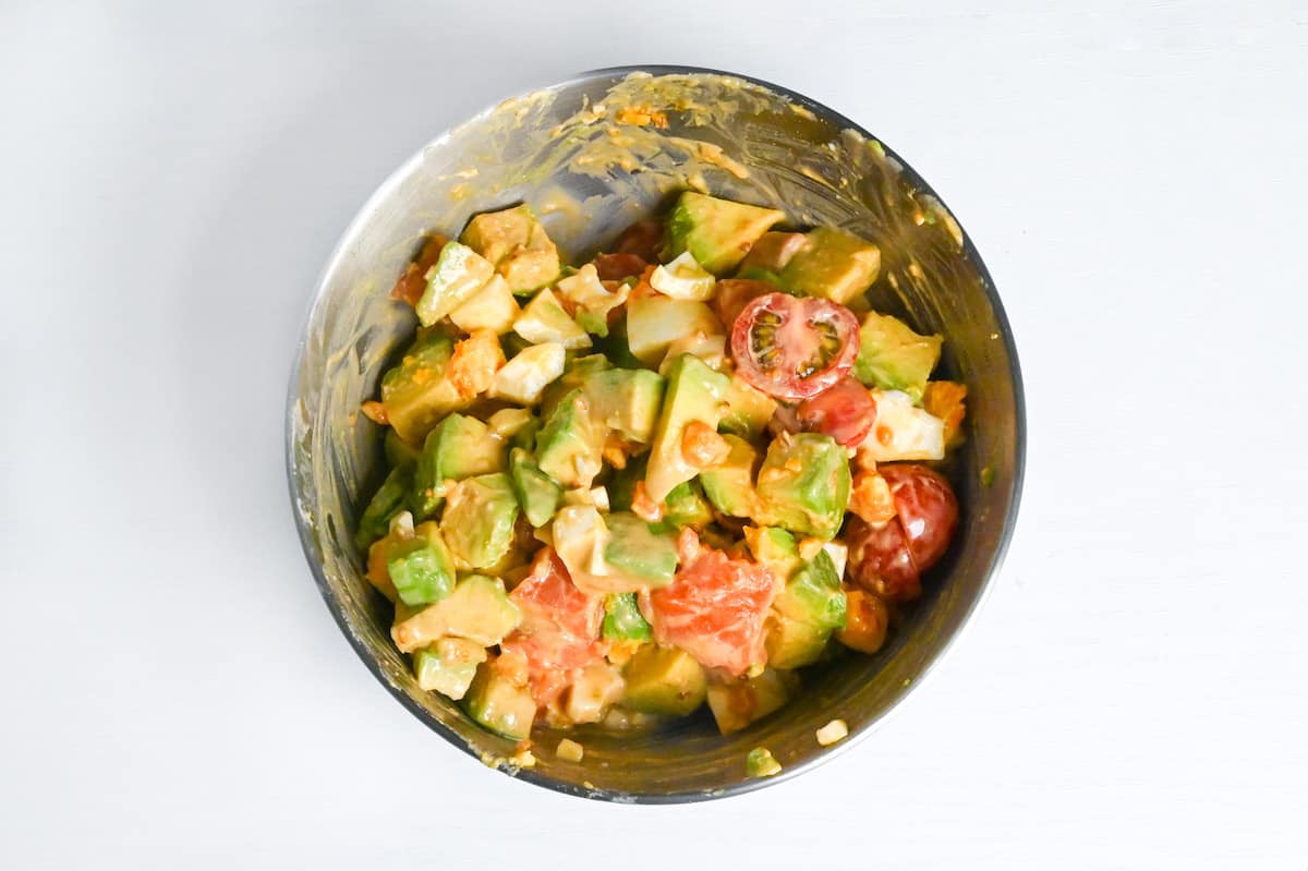 Mixing avocado, boiled egg, tomato and sashimi-grade salmon with sauce to make avocado salad