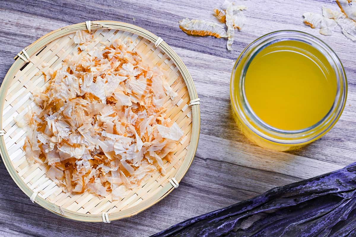 Awase dashi in a glass jar next to a bamboo tray of katsuobushi and hidaka kombu