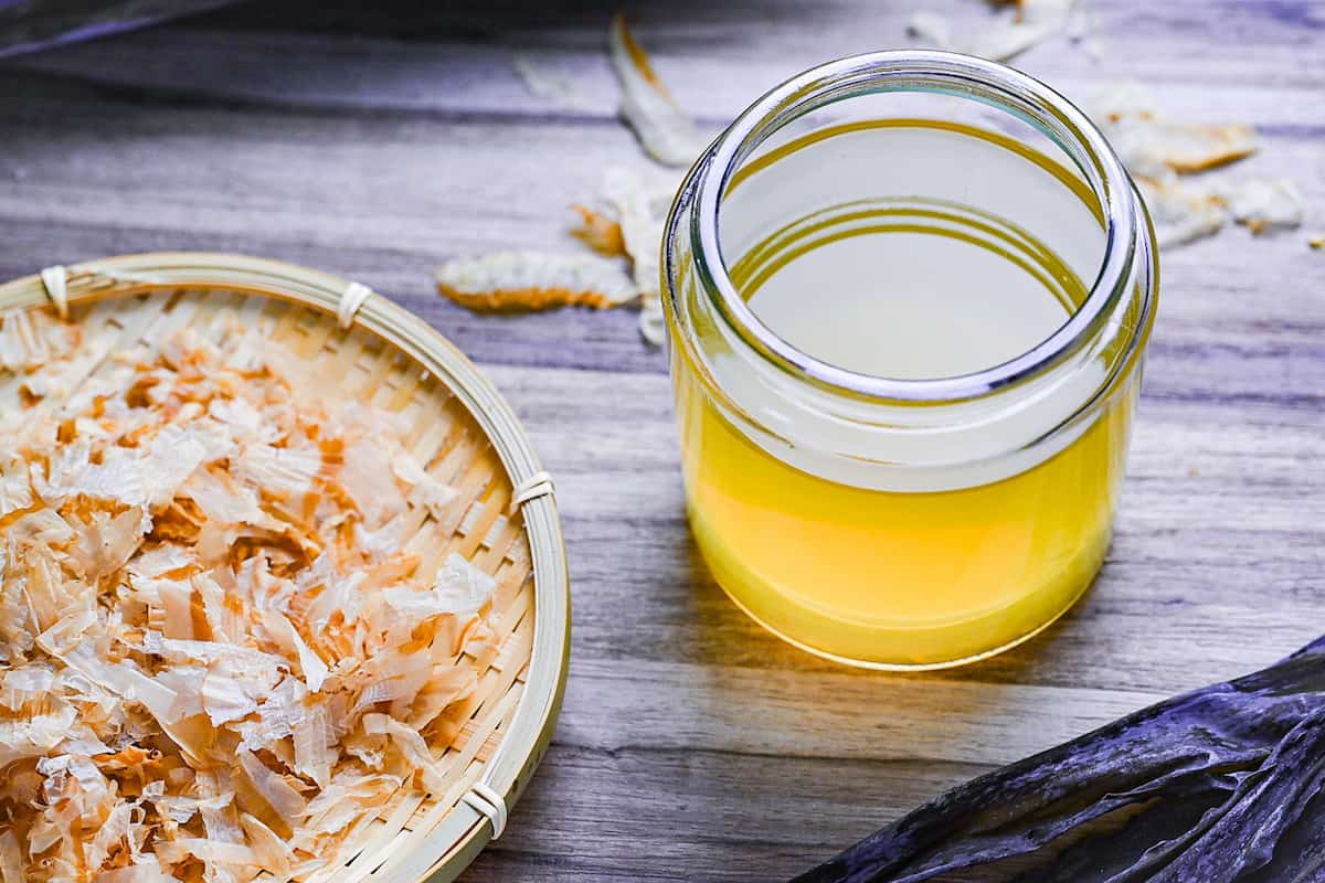 Awase dashi in a glass jar next to a bamboo tray of katsuobushi and hidaka kombu