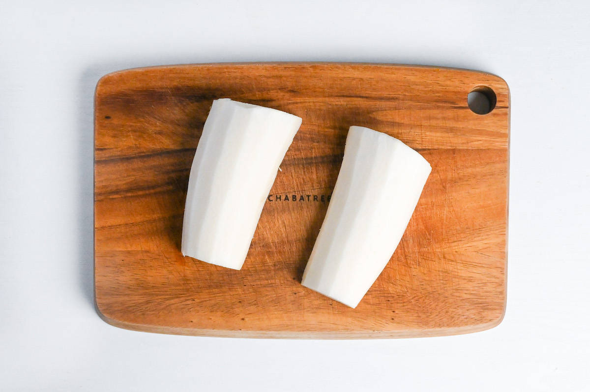 Daikon radish peeled and cut in half lengthways on a wooden chopping board