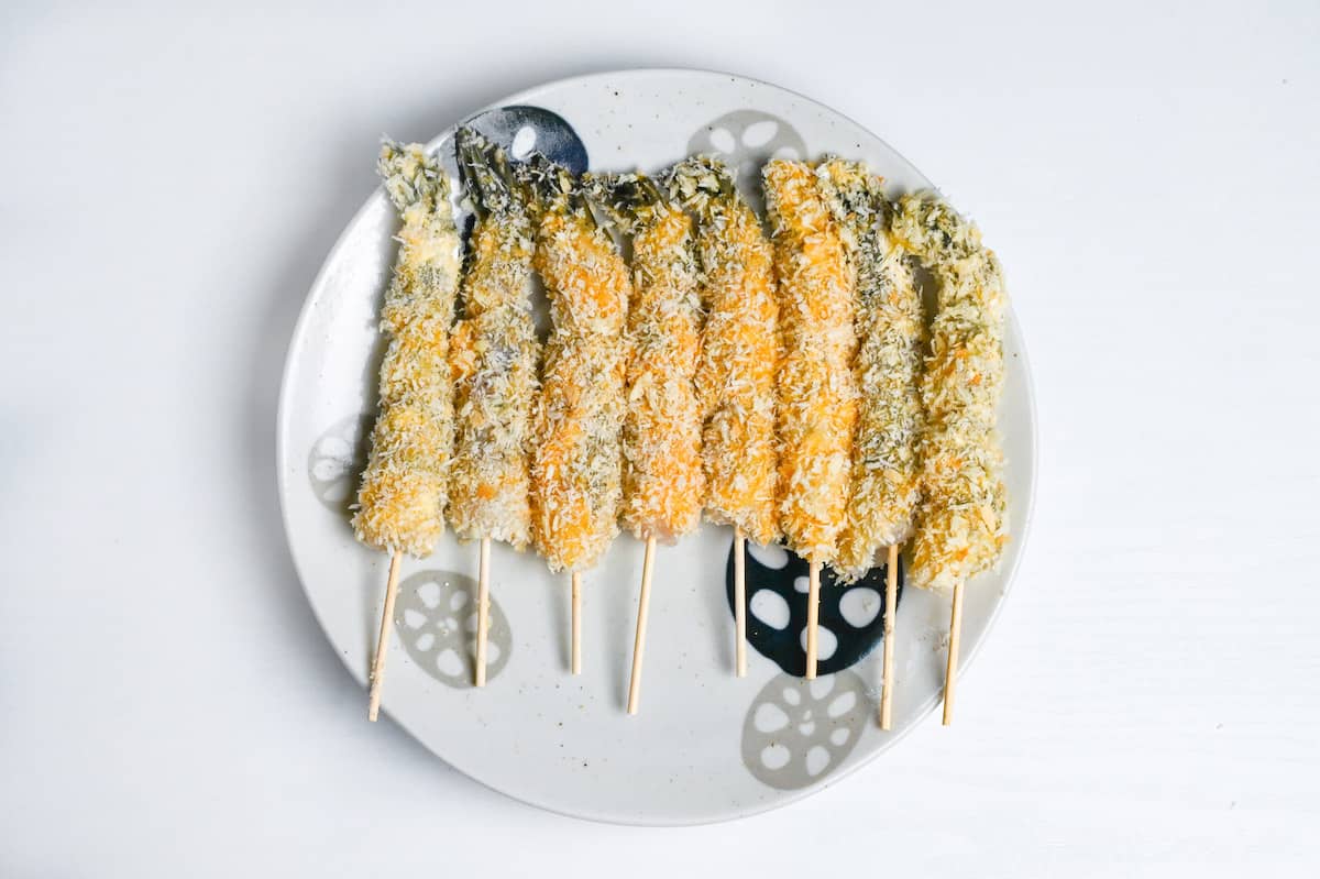 panko coated shrimps on bamboo skewers on a plate