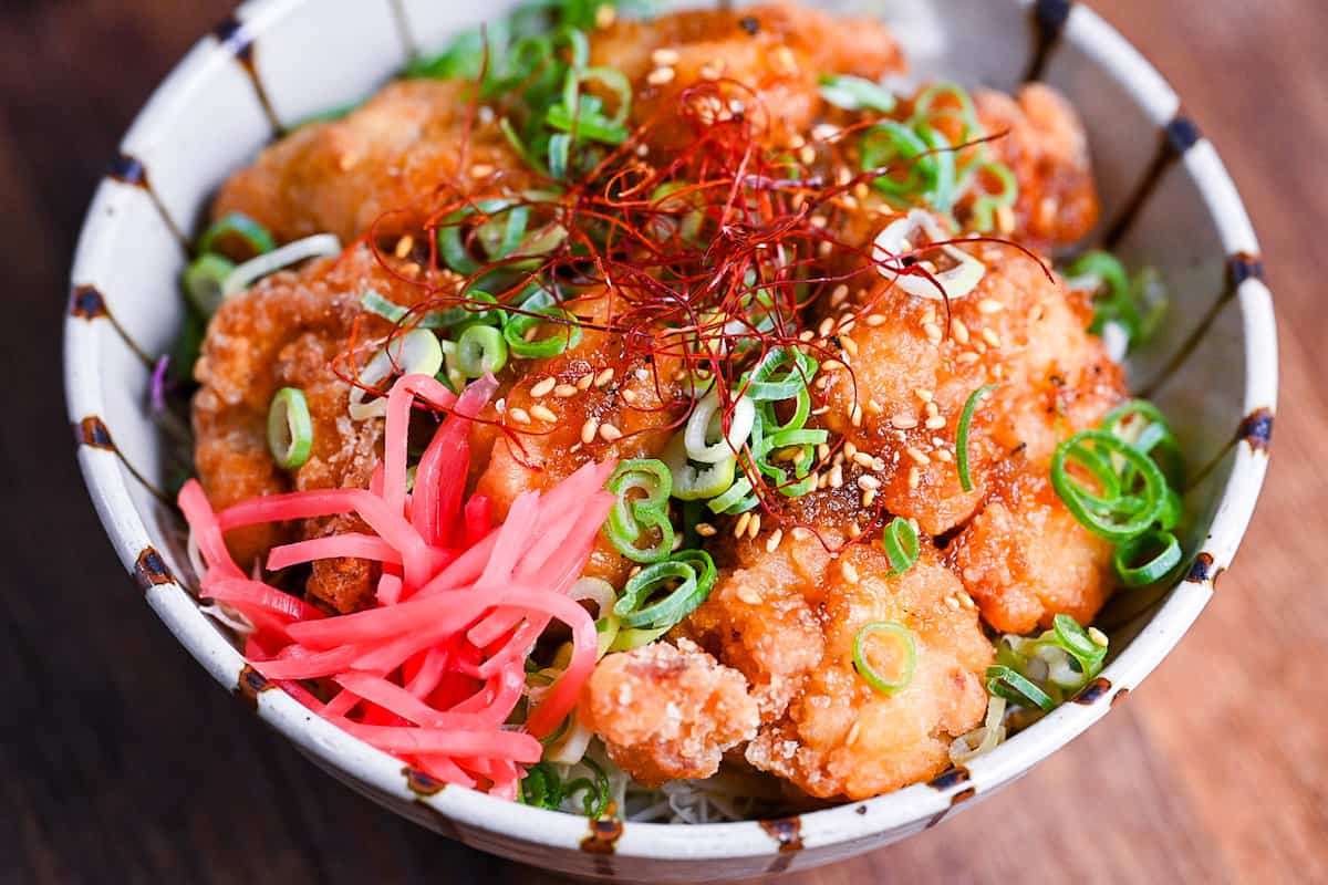 karaage don (Japanese fried chicken bowl) topped with sweet sauce, sesame seeds, chopped green onion, chili threads and pink pickled ginger.