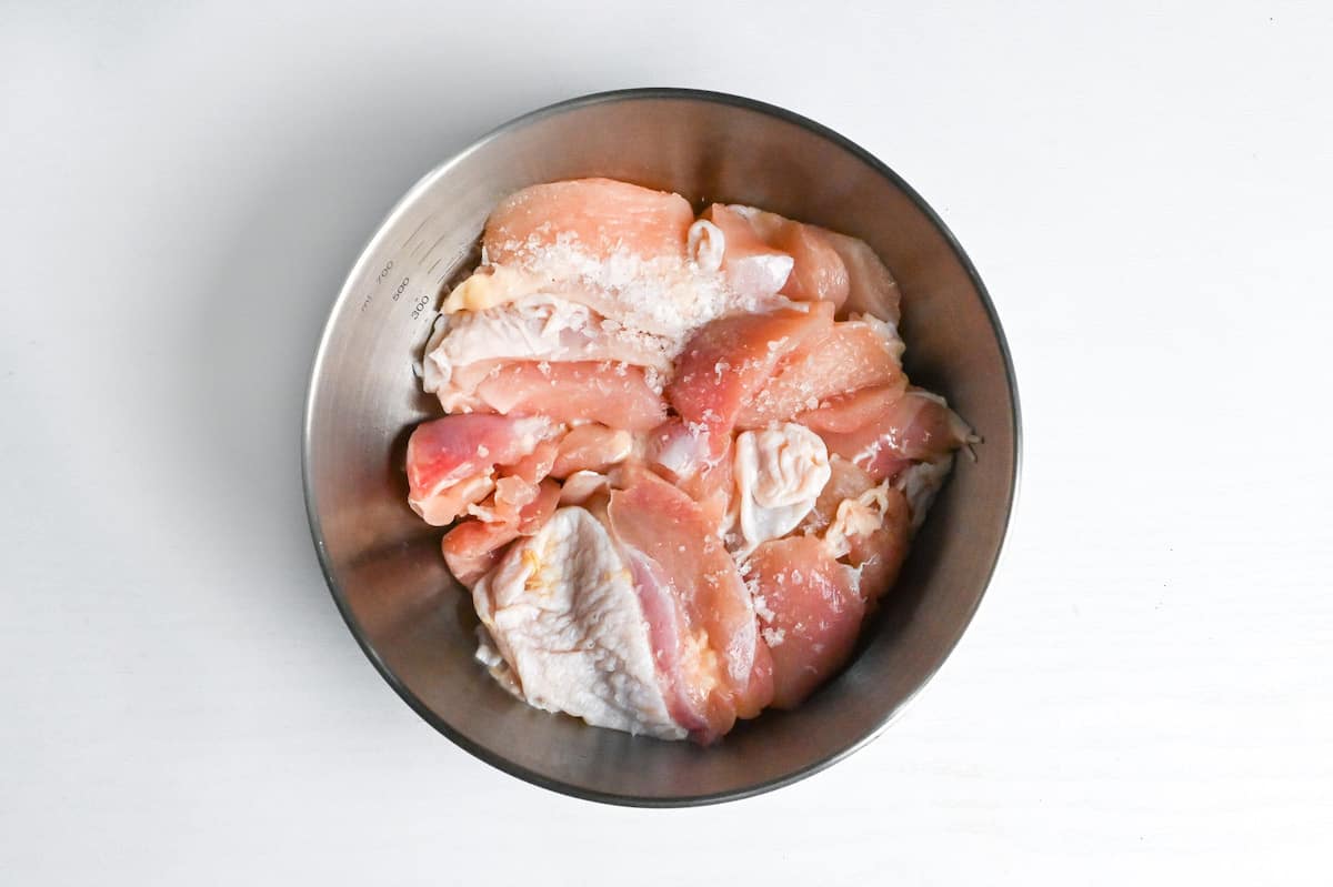 chicken thigh, salt and white pepper in a bowl