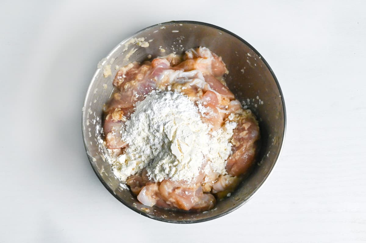chicken thigh, flour and starch in a bowl