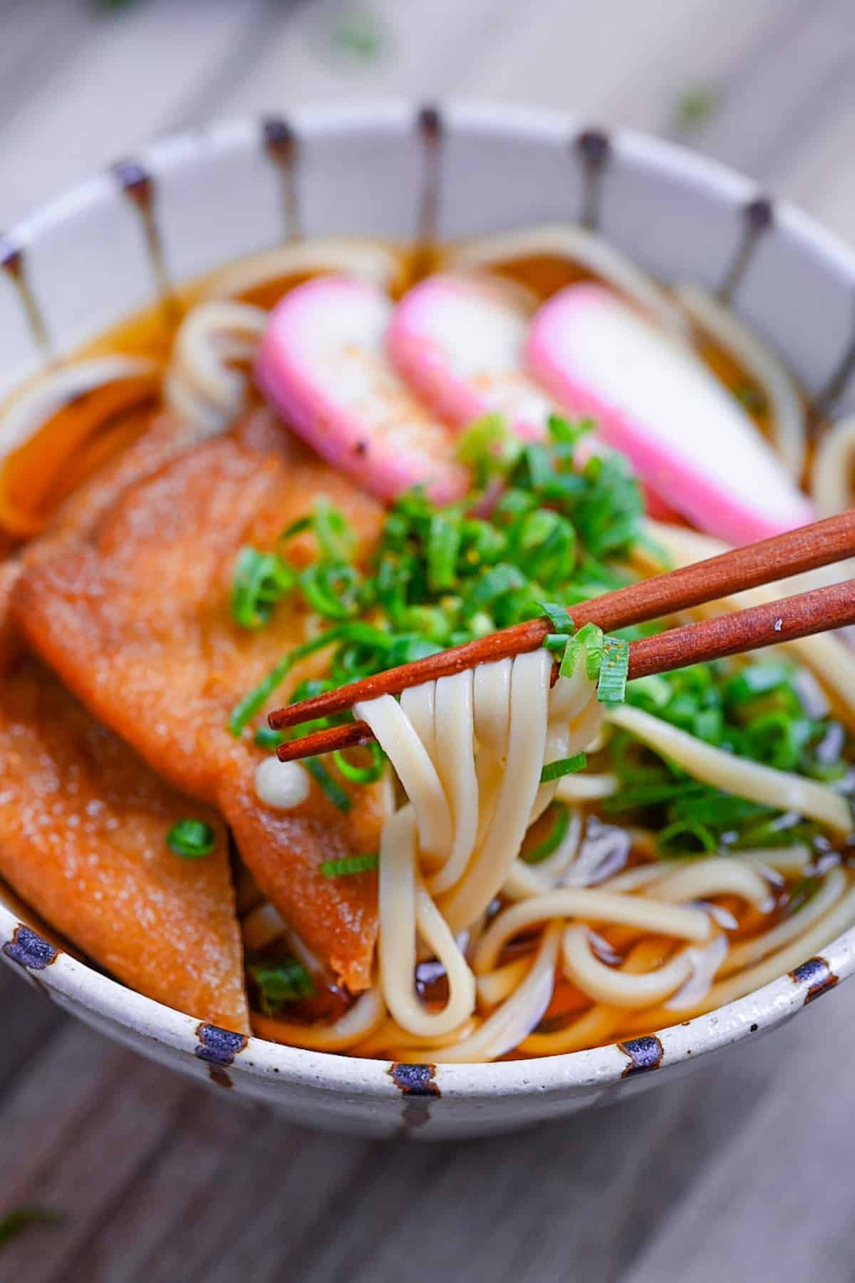 holding udon noodles with wooden chopsticks