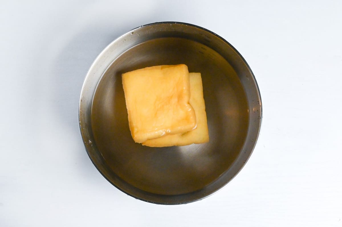 soaking deep fried tofu pouches in bowl of water