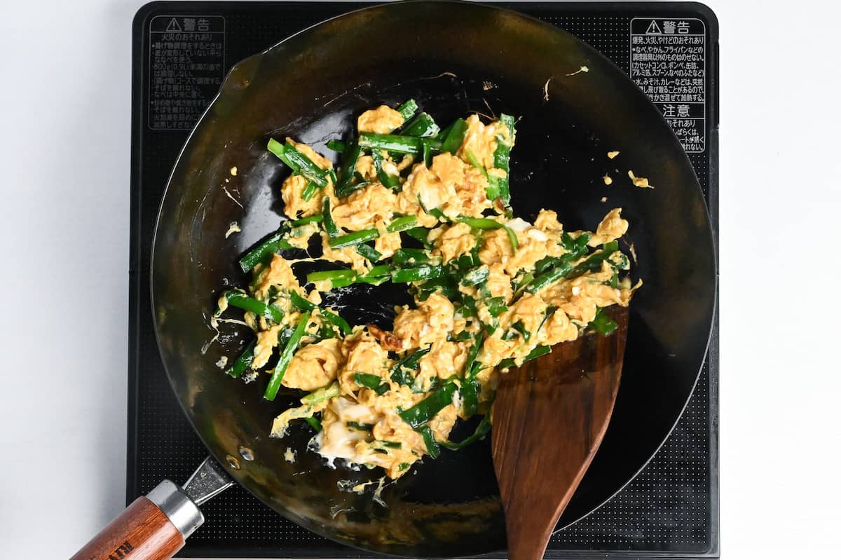 scrambling seasoned eggs and garlic chives in a wok