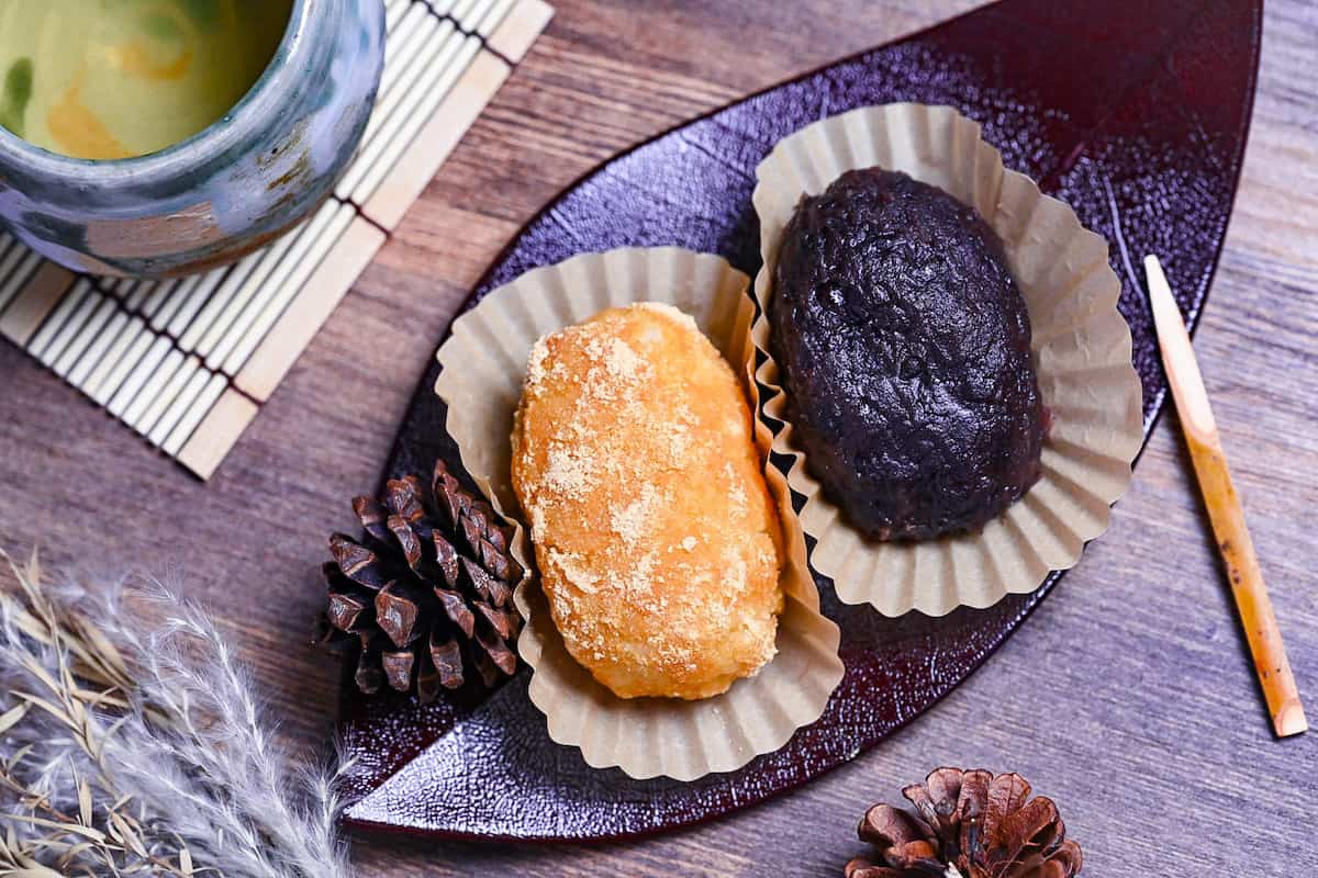 red bean and kinako ohagi on a red leaf-shaped plate with green tea