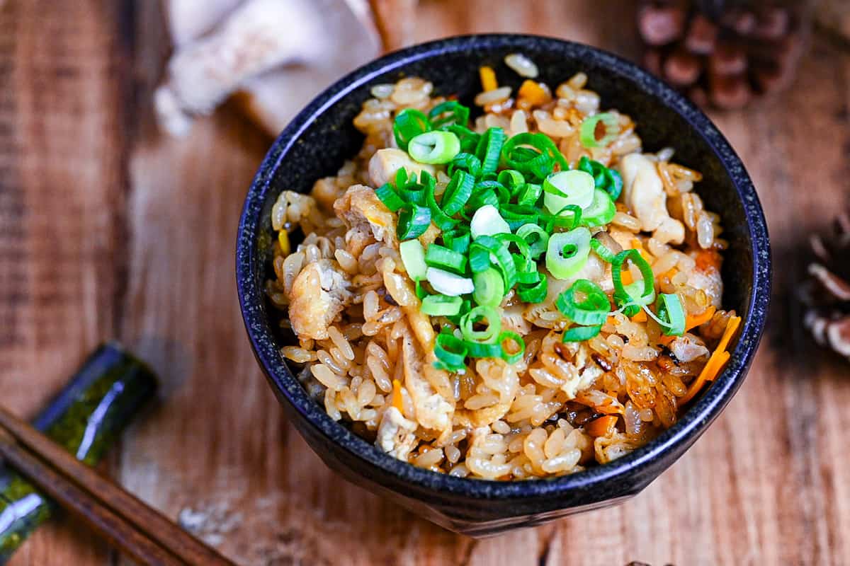 chicken takikomi gohan in a black rice bowl topped with chopped green onion