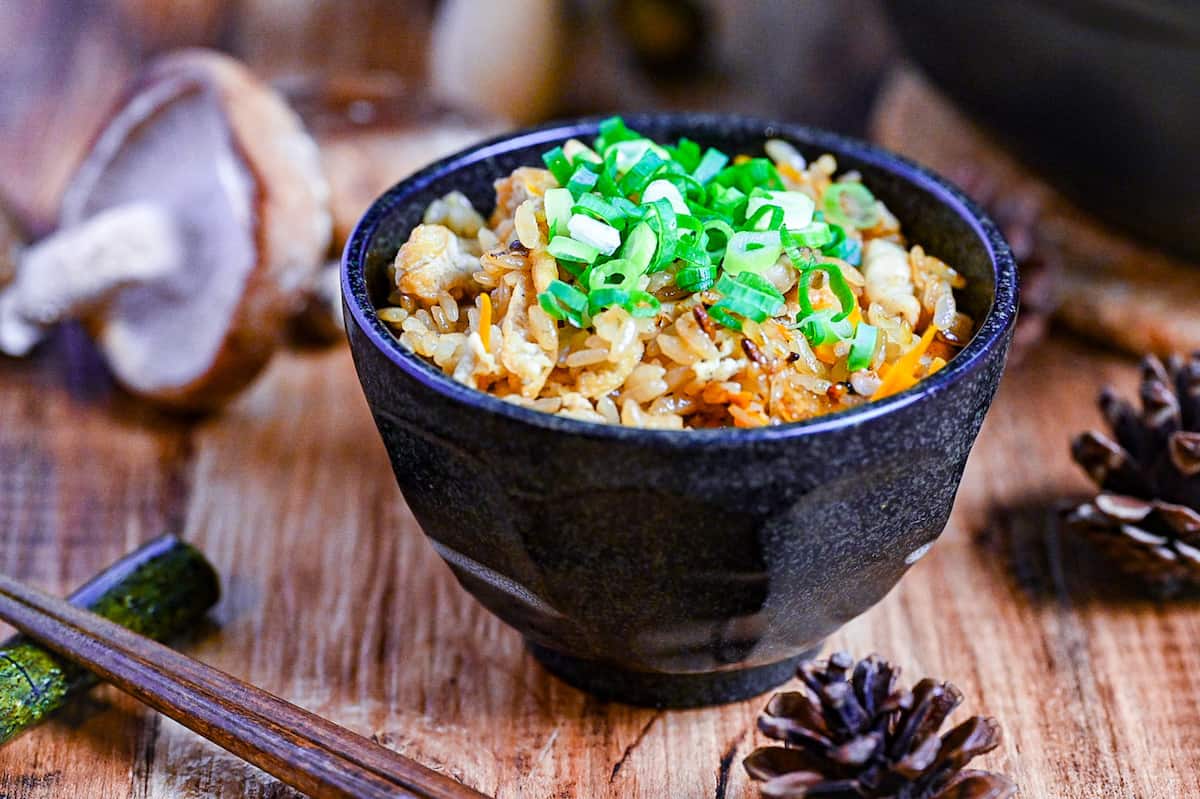 chicken takikomi gohan in a black rice bowl topped with chopped green onion