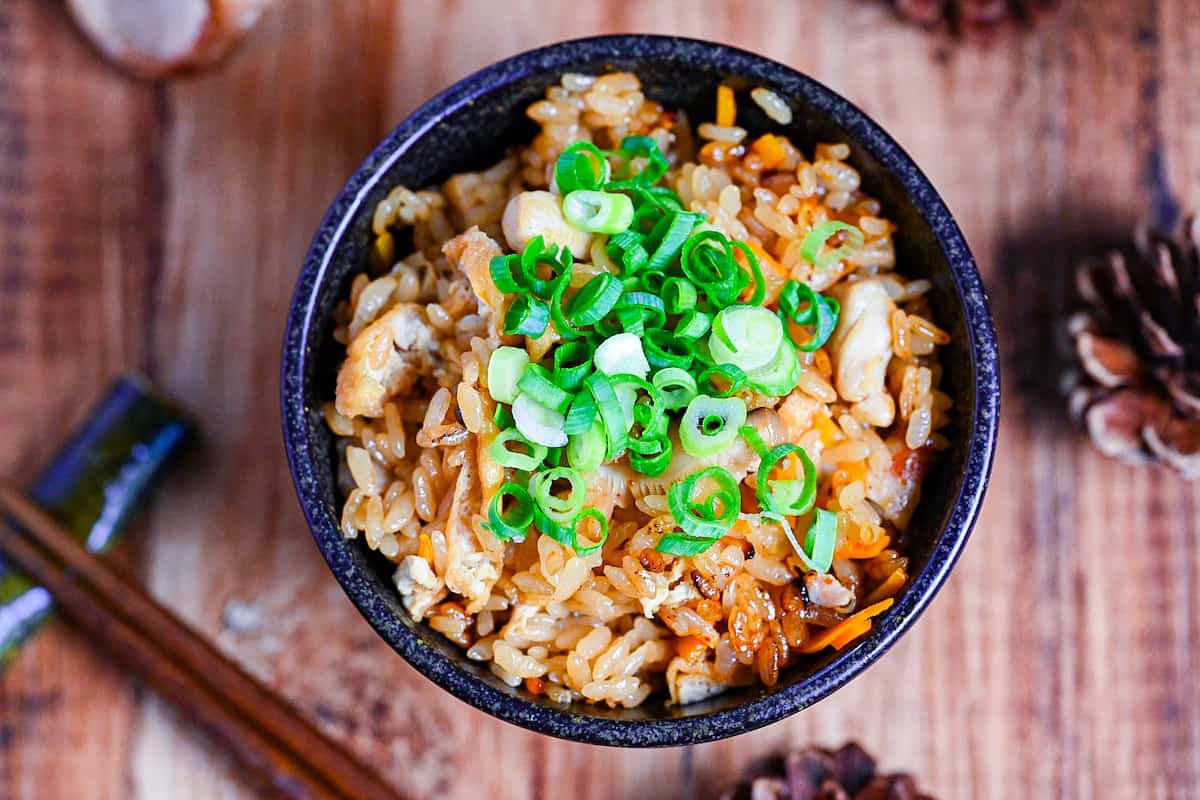 chicken takikomi gohan in a black rice bowl topped with chopped green onion