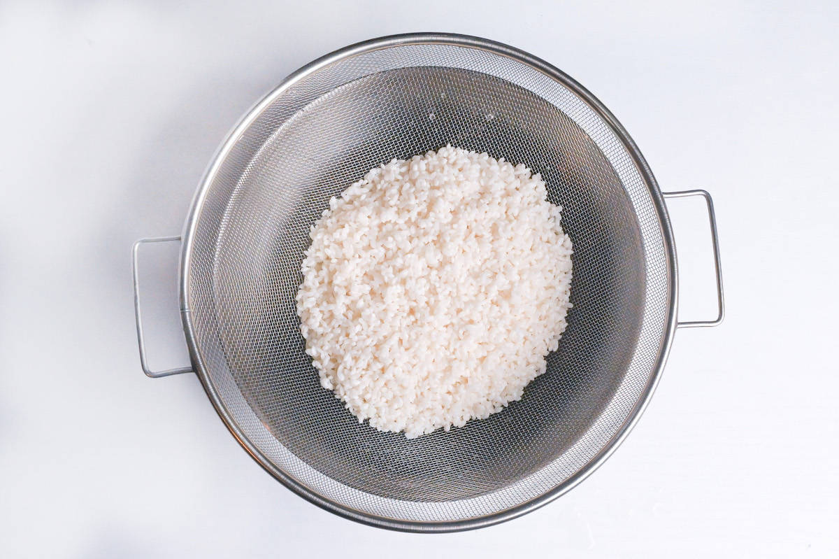 drying rice in a fine mesh sieve over a bowl