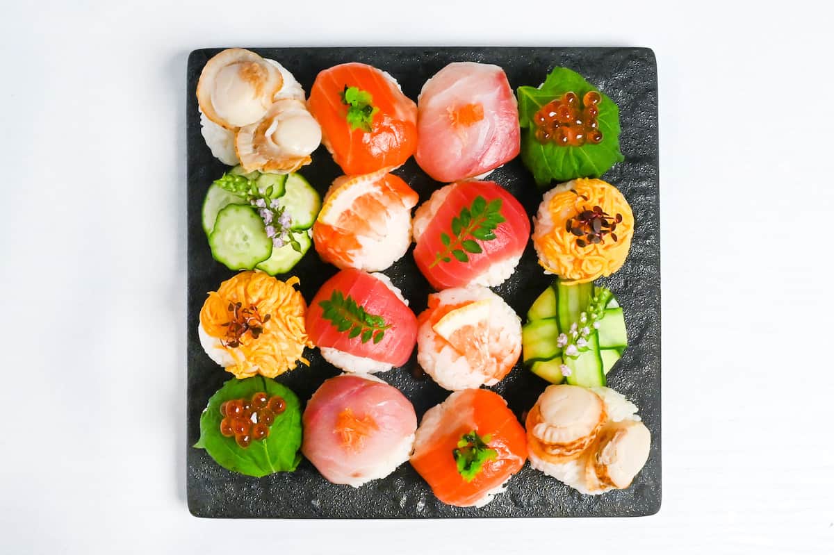 decorative temarizushi made with various seafood, eggs and vegetables topped with leaves, salmon roe, flowers and lemon slices