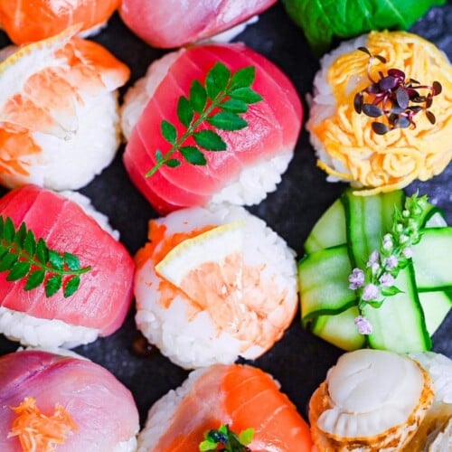 decorative temarizushi made with various seafood, eggs and vegetables topped with leaves, salmon roe, flowers and lemon slices