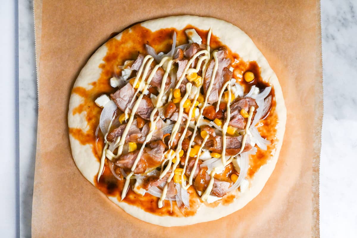 teriyaki chicken pizza topped with corn and drizzled with mayonnaise