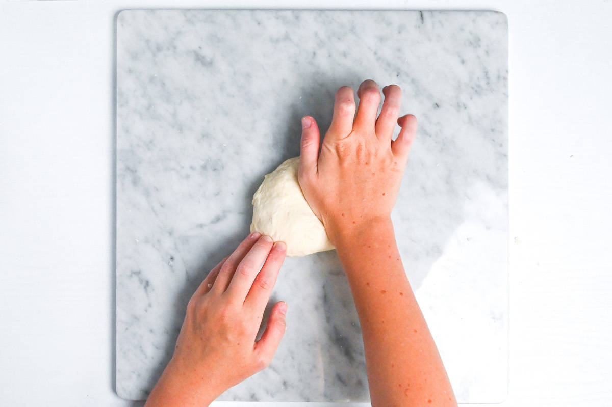 kneading pizza dough on a marble kneading board