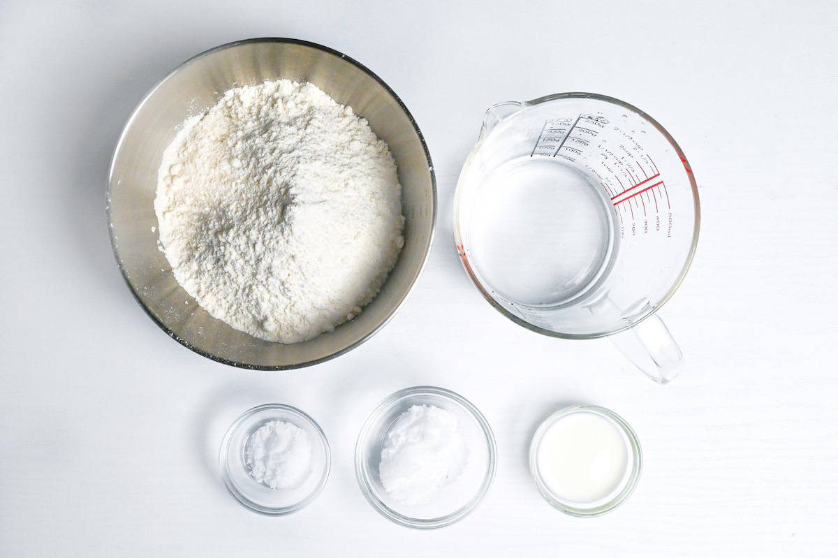 measuring out flour, water, sugar, salt and milk to make pizza dough