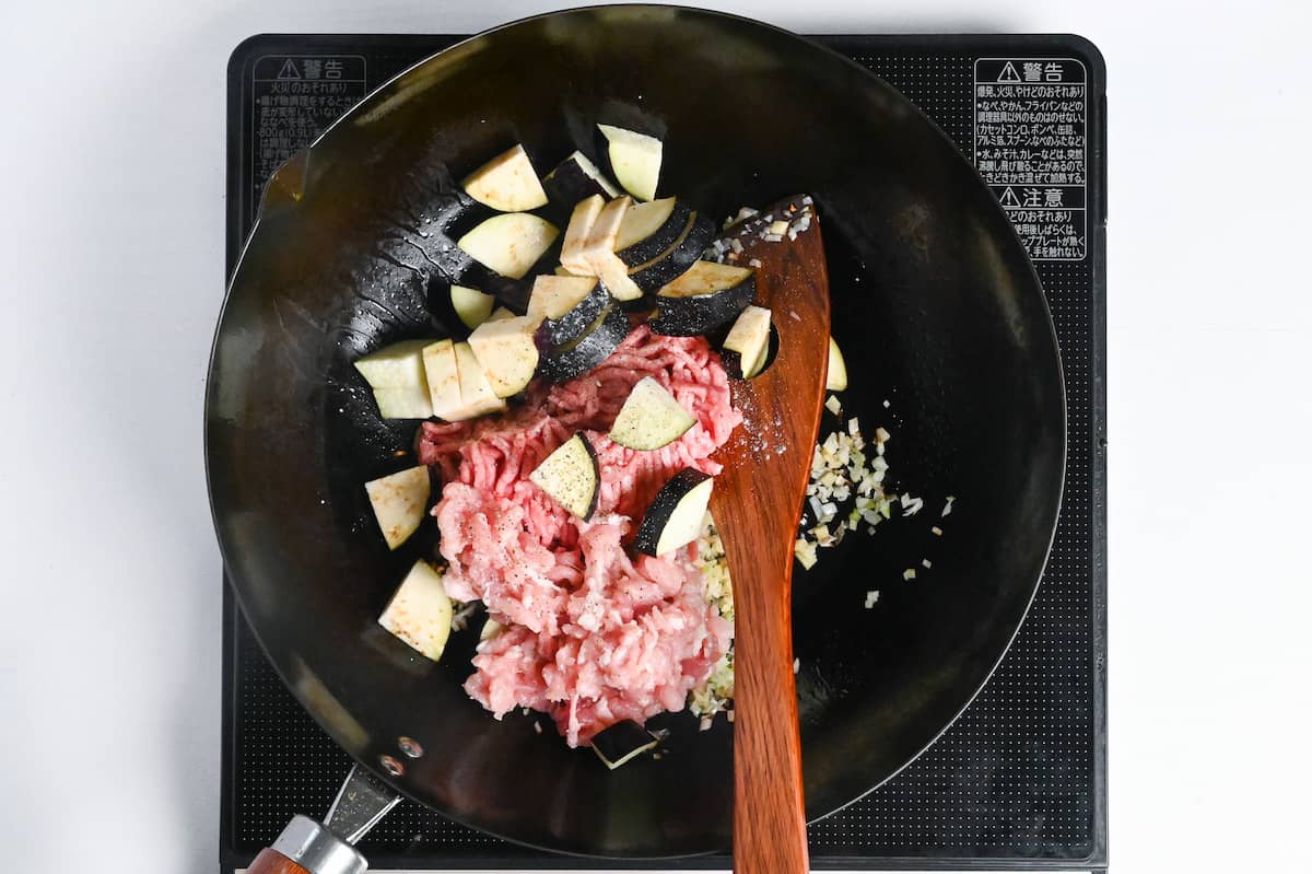 frying pork and eggplant with aromatics in a wok