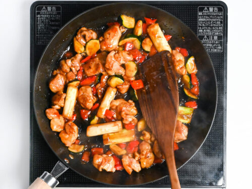 Stir frying chicken and vegetables in yakitori style sauce until thickened and glossy