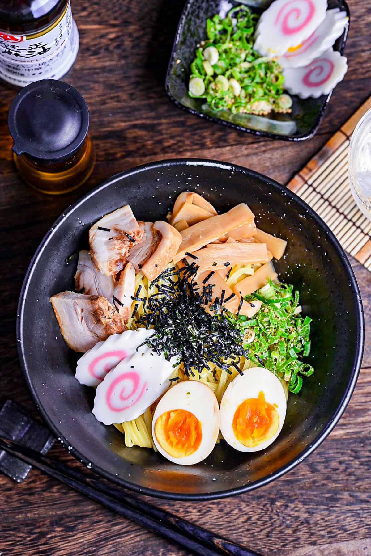 Abura soba soupless ramen in a black bowl topped with ramen egg, narutomaki, menma, chashu, green onion and kizami nori