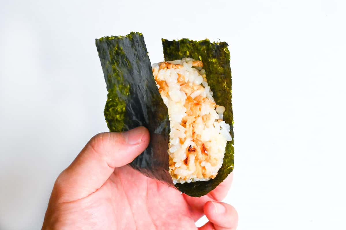 soboro chicken onigiri wrapped in nori held in a hand